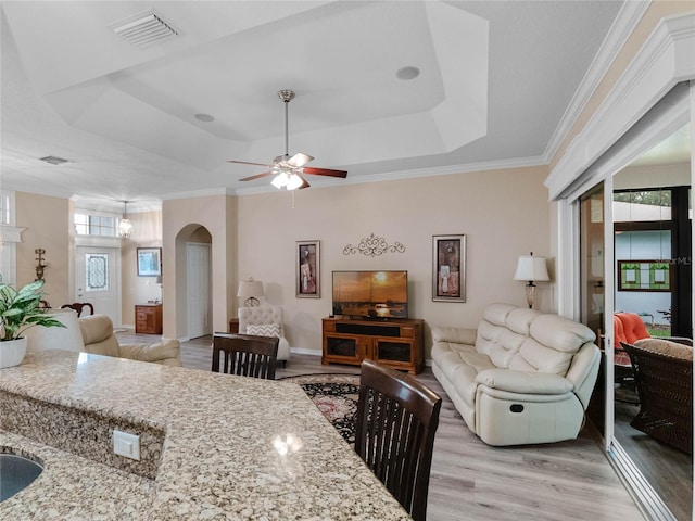 interior space featuring visible vents, light wood finished floors, arched walkways, ceiling fan, and a raised ceiling