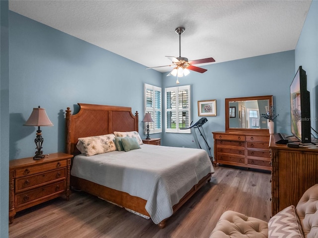 bedroom with a ceiling fan, wood finished floors, and a textured ceiling