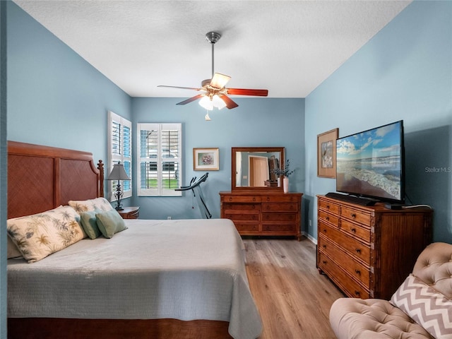 bedroom with a textured ceiling, wood finished floors, and ceiling fan