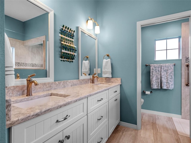 bathroom featuring double vanity, toilet, baseboards, and a sink