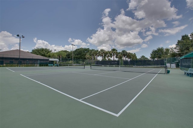 view of tennis court with community basketball court and fence