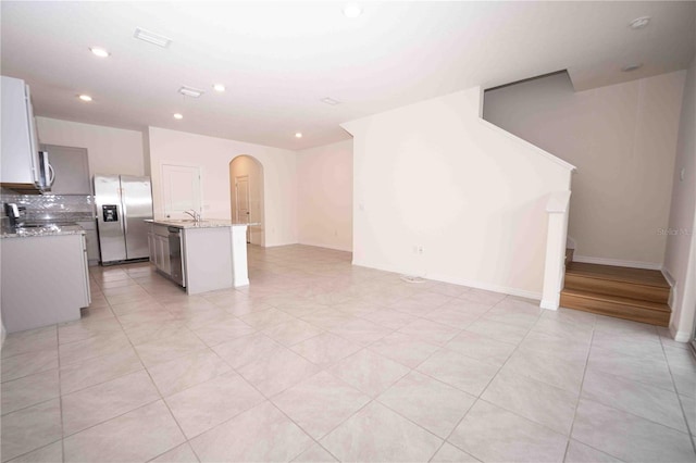 kitchen with a center island, sink, stainless steel appliances, light stone counters, and backsplash