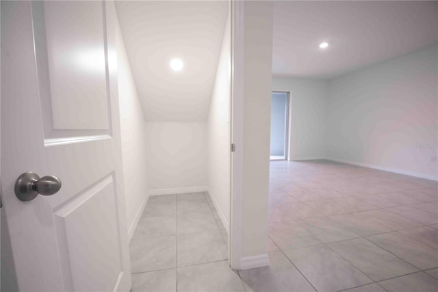 hall with light tile patterned floors and vaulted ceiling