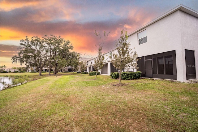 yard at dusk featuring a water view