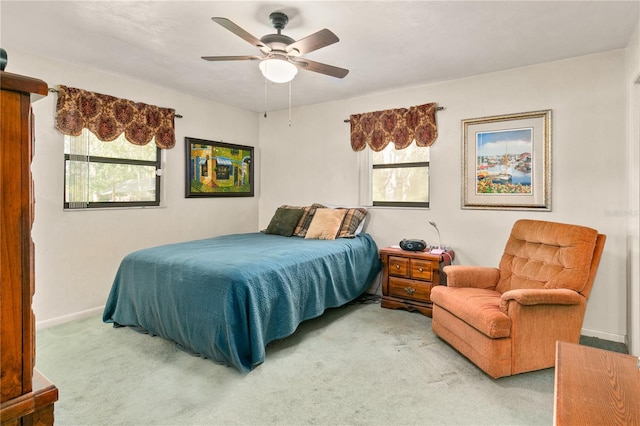 bedroom with ceiling fan, light colored carpet, and multiple windows