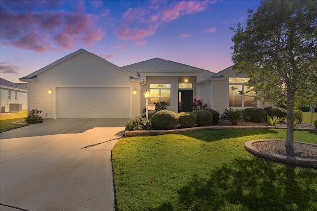 view of front of house with central AC, a yard, and a garage