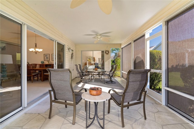 sunroom / solarium featuring ceiling fan with notable chandelier