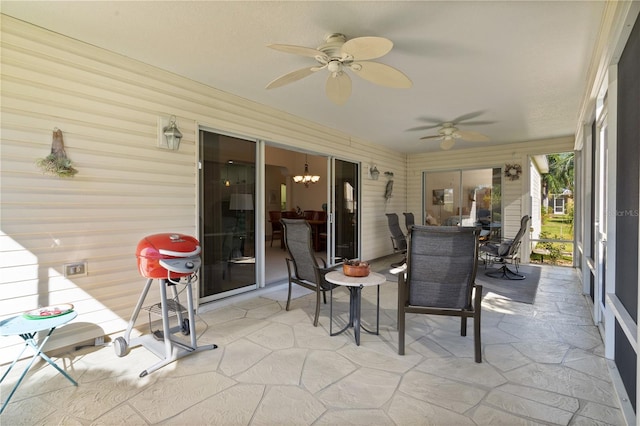 sunroom featuring ceiling fan with notable chandelier