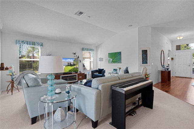 living room with light hardwood / wood-style floors, a healthy amount of sunlight, and lofted ceiling