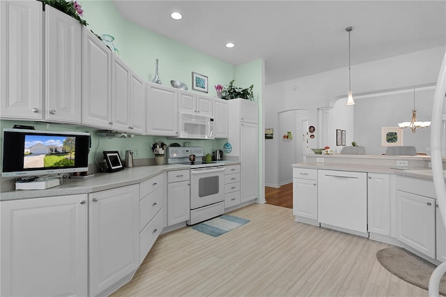 kitchen with white appliances, hanging light fixtures, light hardwood / wood-style floors, white cabinetry, and a chandelier