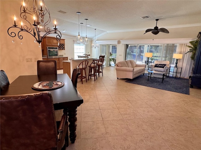 dining space with ornamental molding, a textured ceiling, ceiling fan, light tile patterned floors, and lofted ceiling