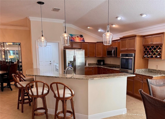 kitchen with decorative light fixtures, ornamental molding, appliances with stainless steel finishes, and vaulted ceiling