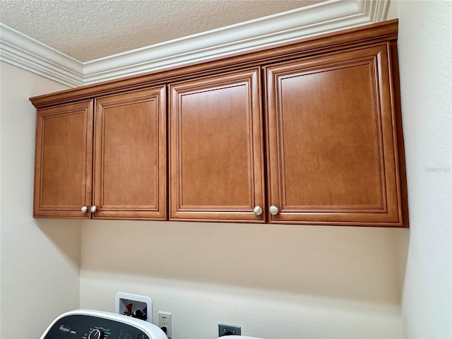 washroom featuring electric dryer hookup, cabinets, washer hookup, ornamental molding, and a textured ceiling