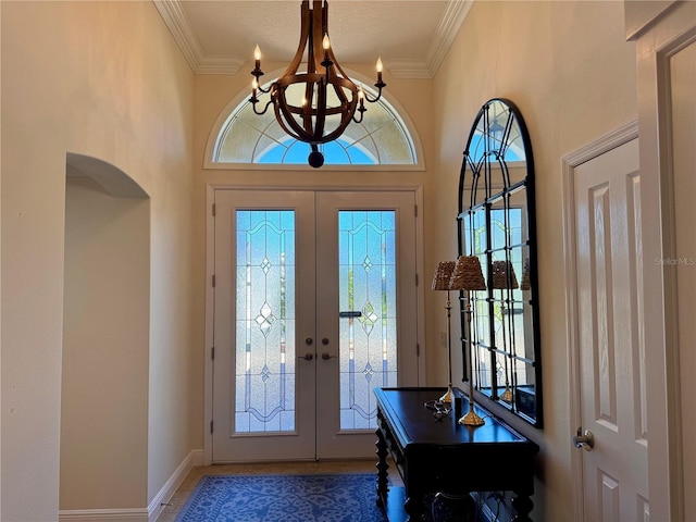 foyer featuring crown molding, french doors, a textured ceiling, and a notable chandelier