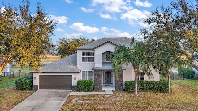 view of front of house with a garage, stucco siding, fence, and a front yard