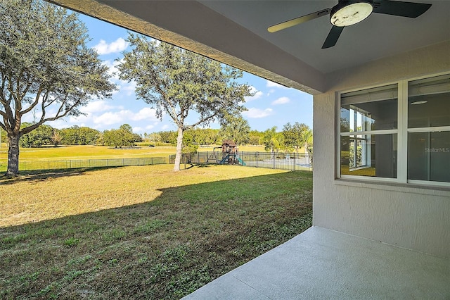 view of yard with playground community, a fenced backyard, and ceiling fan