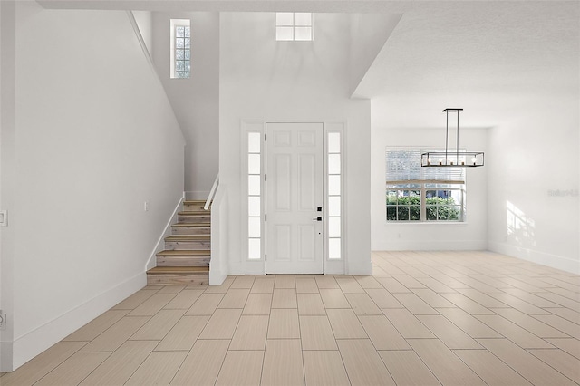 entrance foyer with baseboards, stairs, a chandelier, and wood finish floors