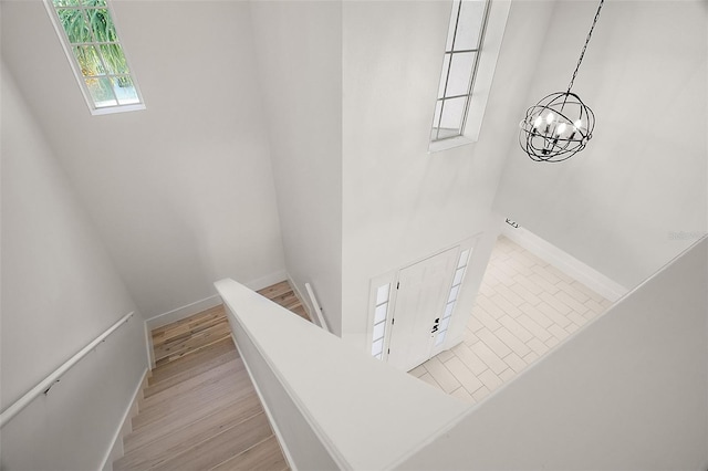 staircase with hardwood / wood-style floors and a chandelier