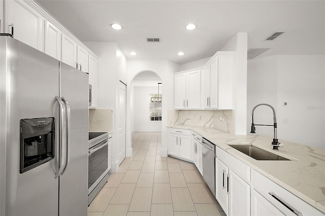 kitchen featuring light stone counters, sink, white cabinets, and appliances with stainless steel finishes