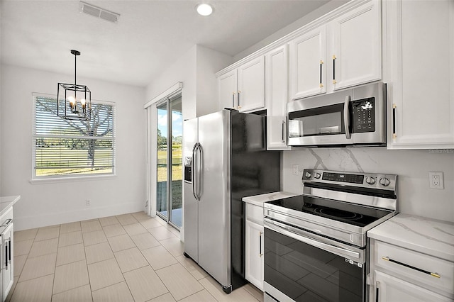 kitchen featuring pendant lighting, light stone countertops, appliances with stainless steel finishes, a notable chandelier, and white cabinetry