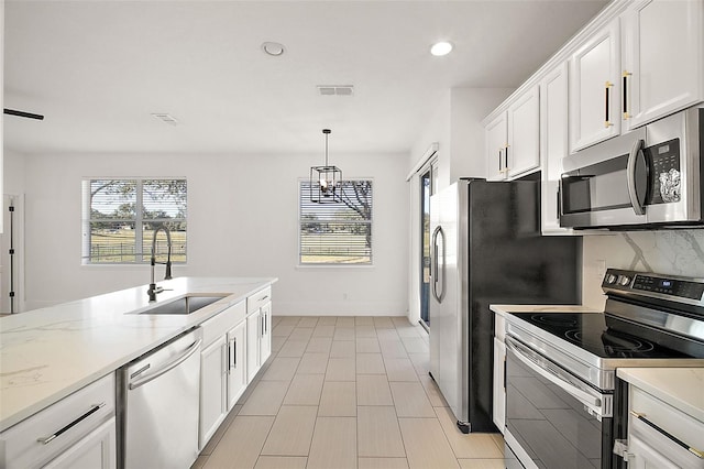 kitchen featuring pendant lighting, white cabinets, sink, light stone countertops, and appliances with stainless steel finishes