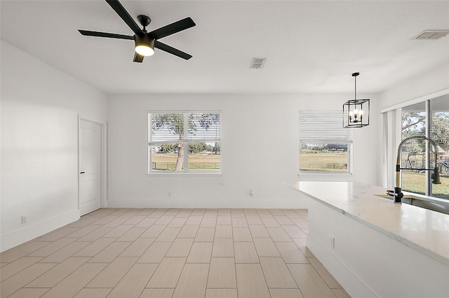 interior space with ceiling fan with notable chandelier, sink, and a wealth of natural light