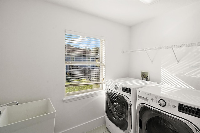 clothes washing area with washer and dryer, sink, and a wealth of natural light