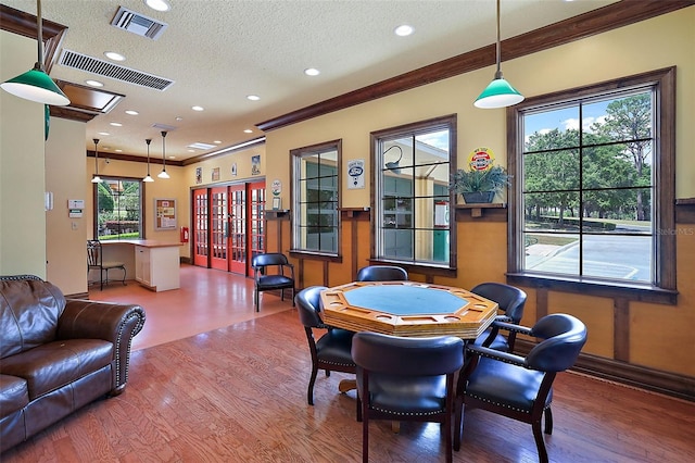 game room featuring a textured ceiling, hardwood / wood-style flooring, plenty of natural light, and ornamental molding