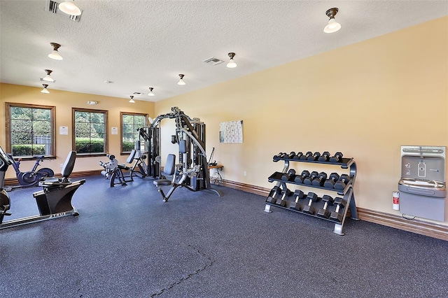 gym featuring baseboards, visible vents, and a textured ceiling