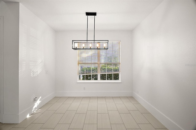 unfurnished dining area with a notable chandelier and baseboards