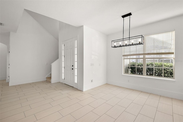 foyer with baseboards, visible vents, an inviting chandelier, and stairs