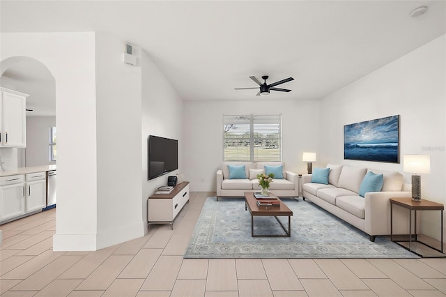 living area featuring arched walkways and ceiling fan