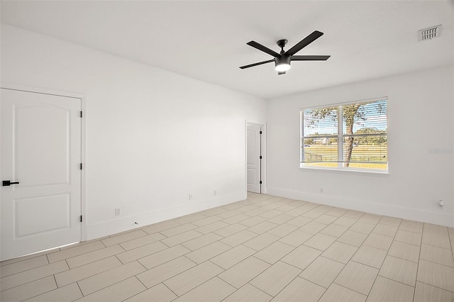 empty room featuring baseboards, visible vents, and a ceiling fan