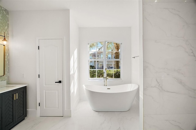 full bathroom featuring marble finish floor, a freestanding bath, and vanity