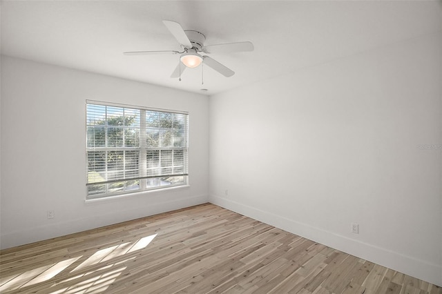 spare room featuring baseboards, ceiling fan, and light wood-style floors