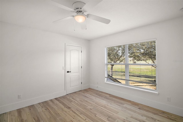 spare room with ceiling fan, light wood finished floors, and baseboards