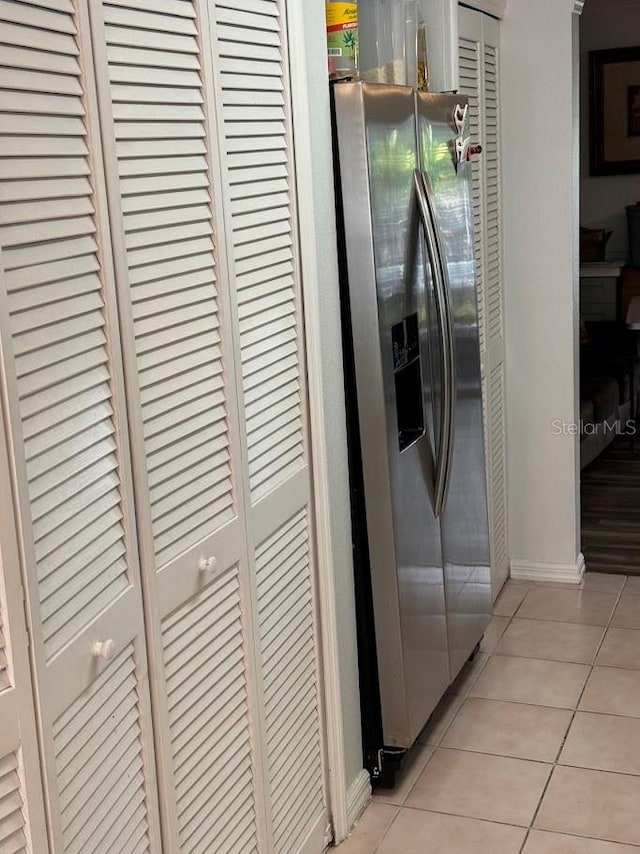 kitchen with stainless steel fridge, white cabinetry, and light tile patterned floors