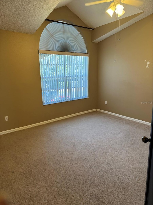 empty room featuring lofted ceiling, a textured ceiling, ceiling fan, carpet floors, and baseboards