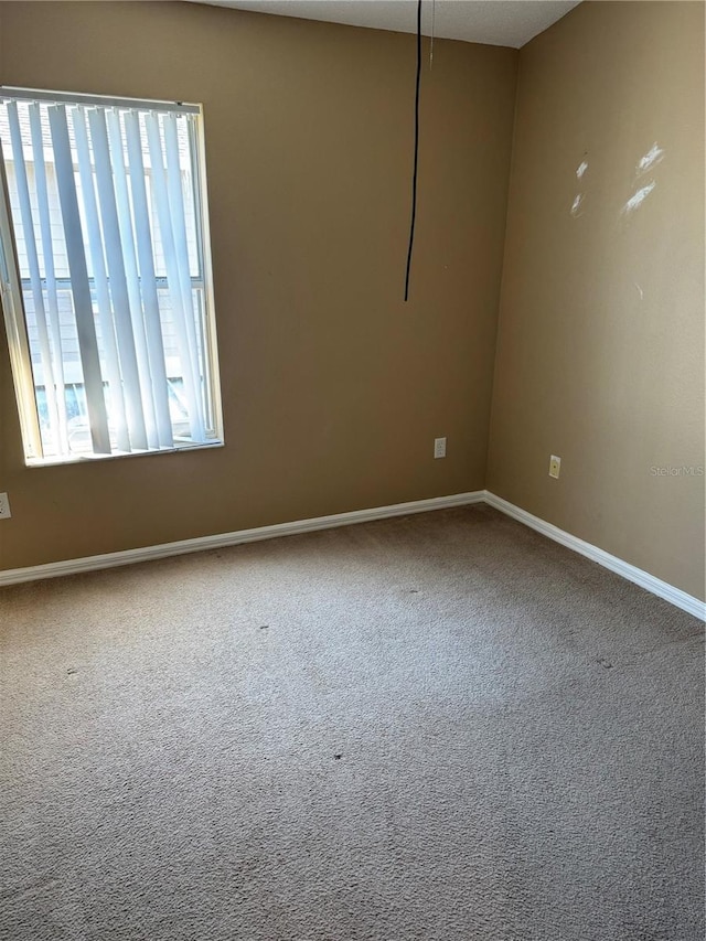 empty room featuring carpet floors, plenty of natural light, and baseboards