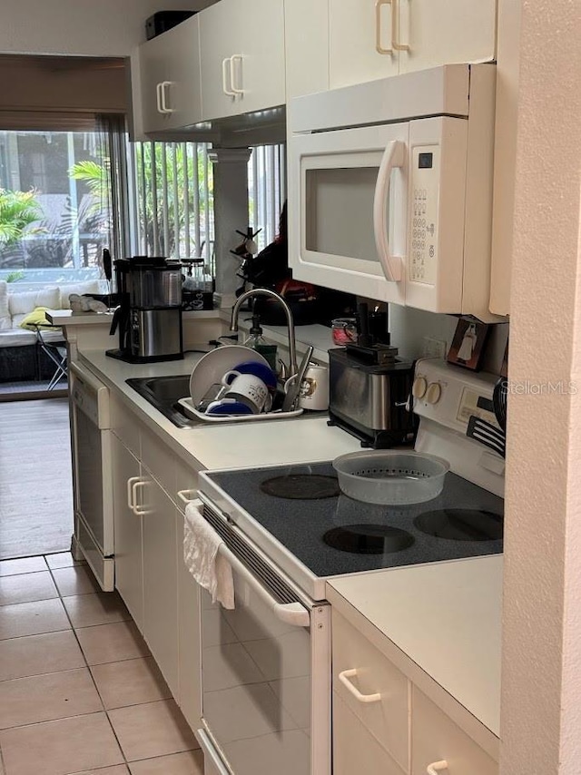 kitchen featuring light countertops, white appliances, a sink, and white cabinetry