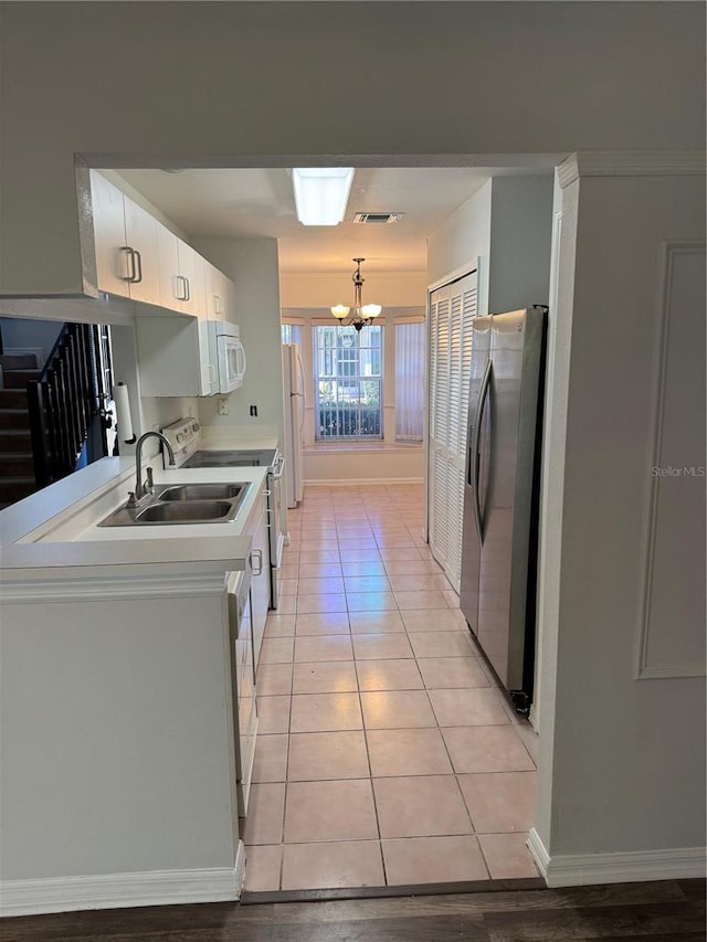 kitchen featuring white appliances, visible vents, decorative light fixtures, light countertops, and white cabinetry