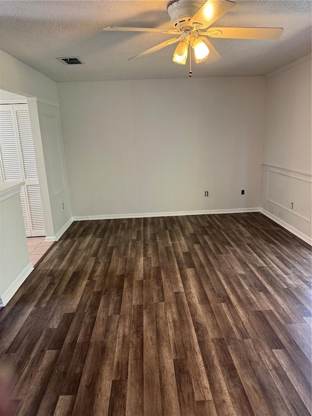 spare room featuring a ceiling fan, a textured ceiling, visible vents, and dark wood-type flooring