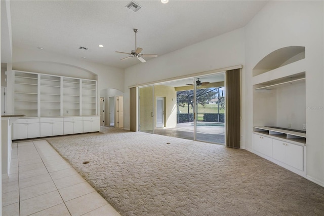 unfurnished living room with ceiling fan, light tile patterned floors, a textured ceiling, and a high ceiling