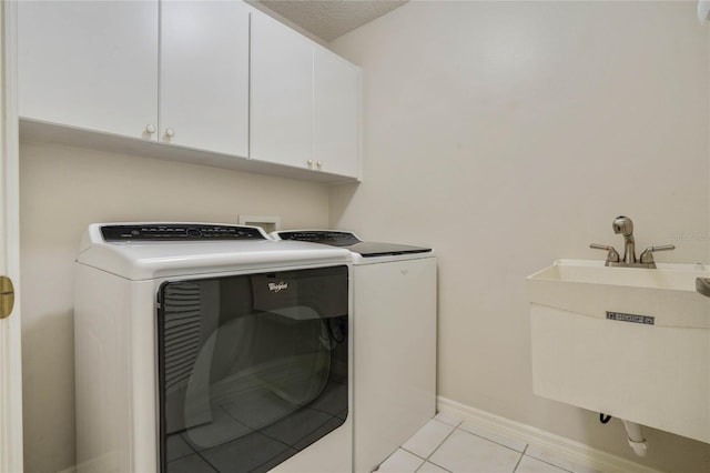 laundry area with cabinets, a textured ceiling, sink, light tile patterned floors, and separate washer and dryer