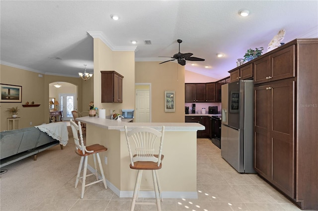 kitchen featuring a kitchen breakfast bar, stainless steel refrigerator with ice dispenser, kitchen peninsula, lofted ceiling, and light tile patterned floors