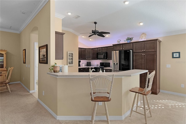 kitchen with a breakfast bar area, kitchen peninsula, crown molding, and black appliances