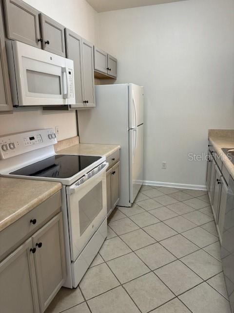 kitchen featuring light tile patterned floors, white appliances, and gray cabinetry