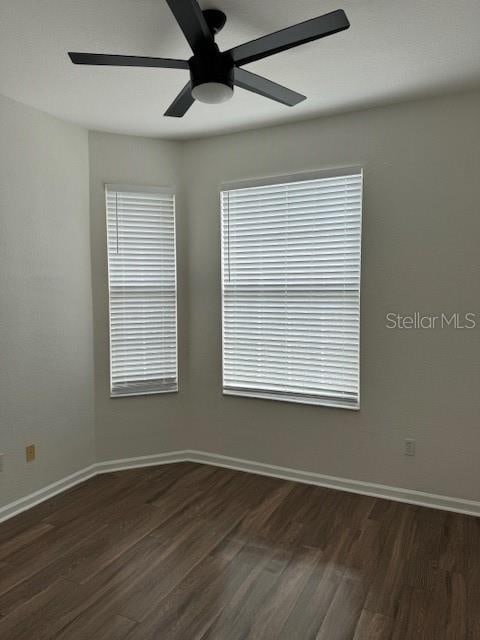 unfurnished room featuring ceiling fan and dark wood-type flooring