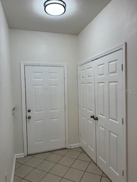 entryway featuring light tile patterned floors and a textured ceiling