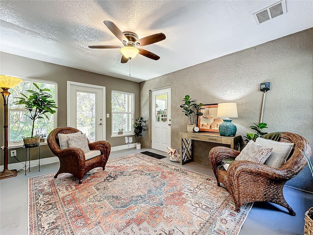 sitting room with concrete flooring, a textured ceiling, and ceiling fan